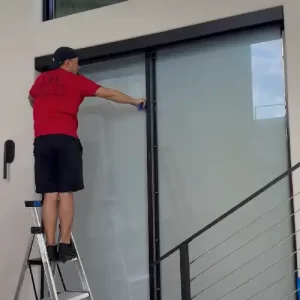 Professional window tint installers Miami applying high-quality smart film to a commercial glass partition.