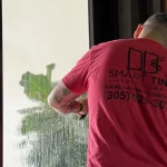 A professional installs solar window film in a miami home